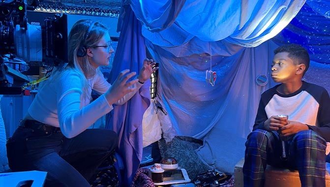 College student directing young boy during the production of cinema trailer